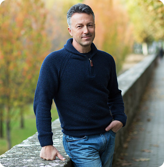 A middle-aged man stands on a bridge