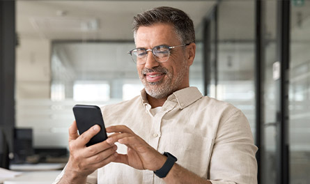 A middle-aged man looks at his phone in the office