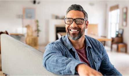 A middle-aged man sits on a couch smiling